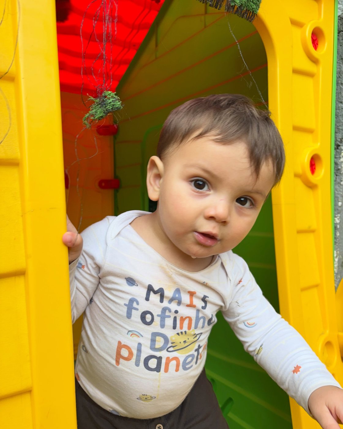 Criança brincando na casinha colorida do pátio