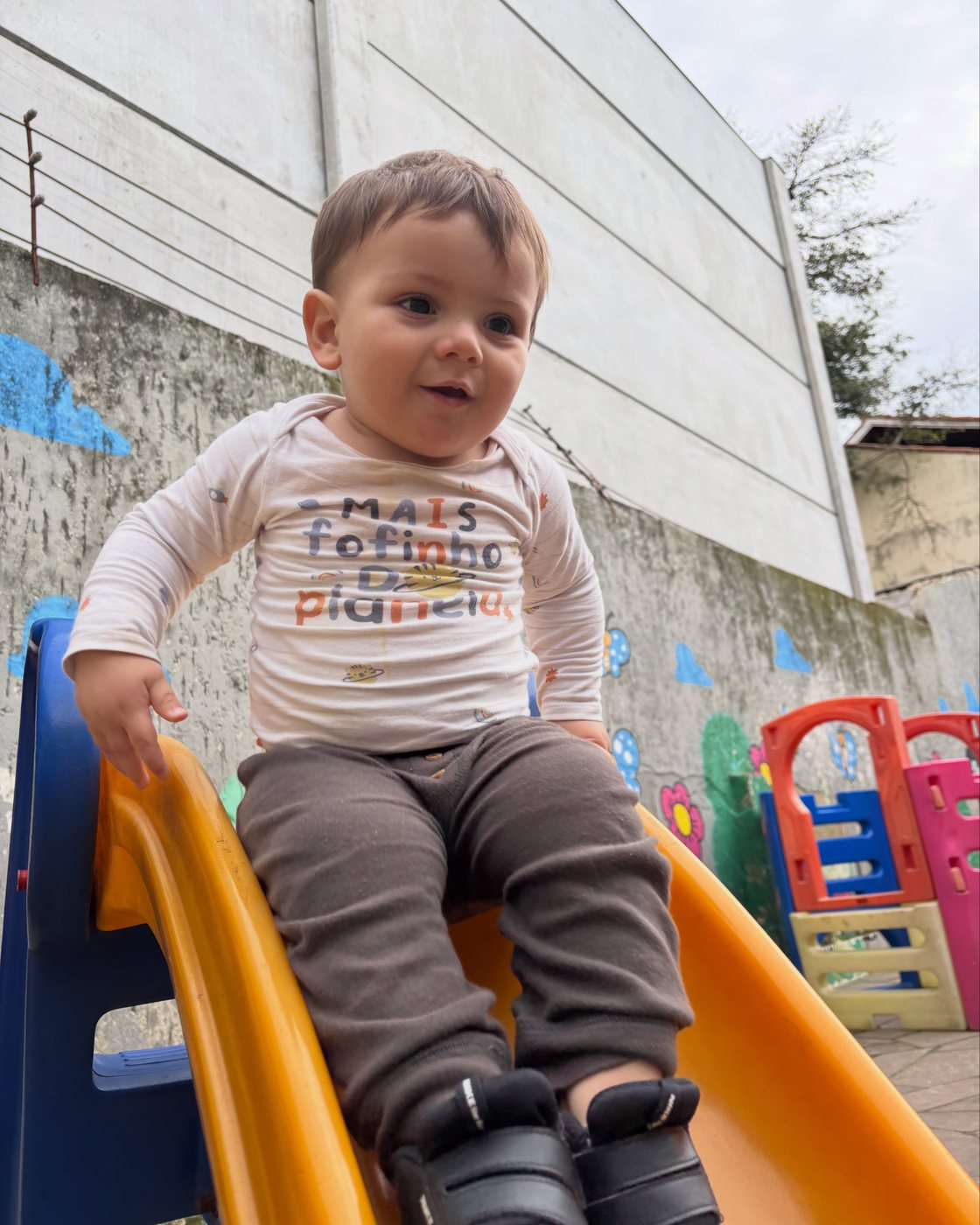 Bebê brincando no escorregador do pátio da Escola Amor de Mãe