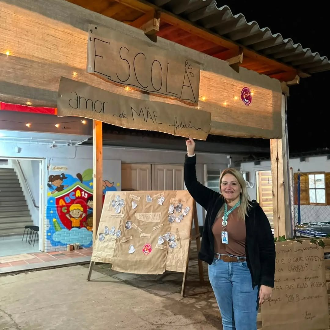 Entrada da unidade Filial da Escola Amor de Mãe, com placa de madeira